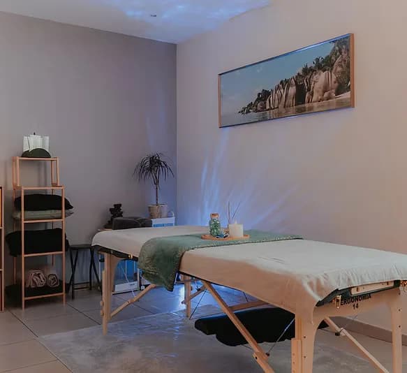 Le cabinet : table de massage, lumière tamisée et étagère de linge